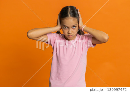 Frustrated young school girl kid covering ears ignoring unpleasant noise loud voices avoiding advice 129997472