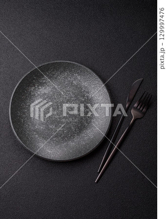 Empty round black plate for food, kitchen utensils on dining table. Empty plate Empty round black plate for food, kitchen utensils on dining table. Empty plate 129997476
