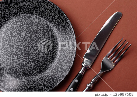 Empty round black plate for food, kitchen utensils on dining table. Empty plate 129997509