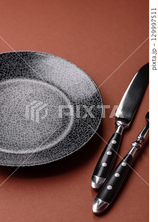 Empty round black plate for food, kitchen utensils on dining table. Empty plate Empty round black plate for food, kitchen utensils on dining table. Empty plate 129997511
