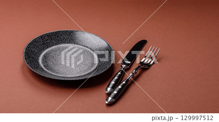 Empty round black plate for food, kitchen utensils on dining table. Empty plate Empty round black plate for food, kitchen utensils on dining table. Empty plate 129997512
