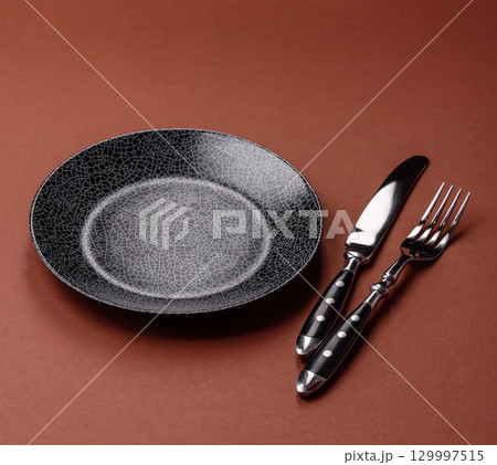 Empty round black plate for food, kitchen utensils on dining table. Empty plate Empty round black plate for food, kitchen utensils on dining table. Empty plate 129997515