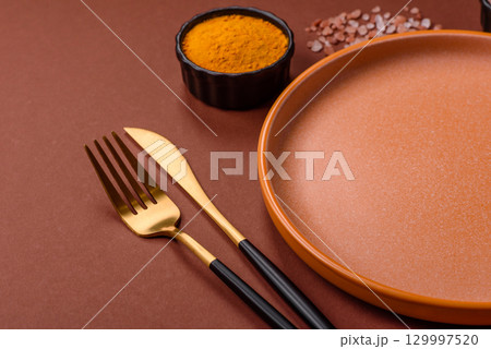 Empty round black plate for food, kitchen utensils on dining table. Empty plate 129997520