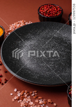 Empty round black plate for food, kitchen utensils on dining table. Empty plate 129997538