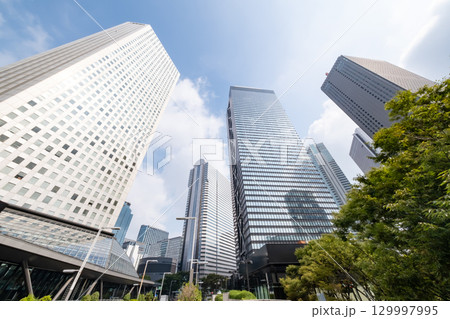 街路樹と高層ビルを見上げるオフィス街の風景 129997995