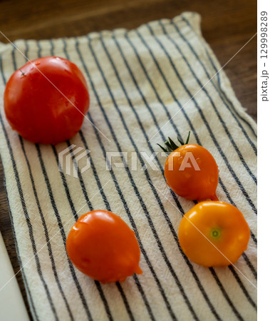 Close-up of four small tomatoes on a cloth napkin in the kitchen. Close-up of four small tomatoes on a cloth napkin in the kitchen. 129998289
