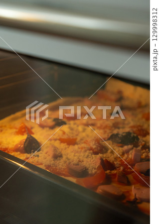 Pizza with pepperoni and sausage cheese is baked in the oven in kitchen or in family restaurant.  129998312