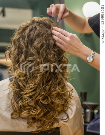 Girl in a beauty salon after styling with a gorgeous hairdo Girl in a beauty salon after styling with a gorgeous hairdo 129998585