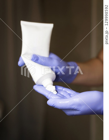 A cosmetologist squeezes cream out of a large tube 129998592