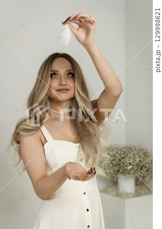 young beautiful blonde girl stands among feathers young beautiful blonde girl stands among feathers 129998621