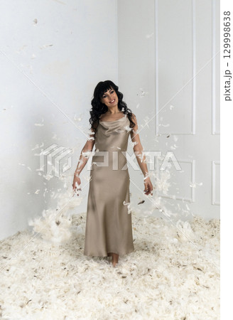 beautiful slender girl white feathers are flying around her 129998638