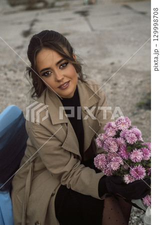 brunette girl in beige coat sits on chair among rocks brunette girl in beige coat sits on chair among rocks 129998708