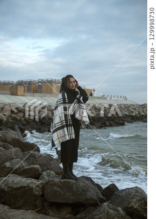 a beautiful young girl with long dark hair stands on the seashore the wind blow a beautiful young girl with long dark hair stands on the seashore the wind blow 129998730