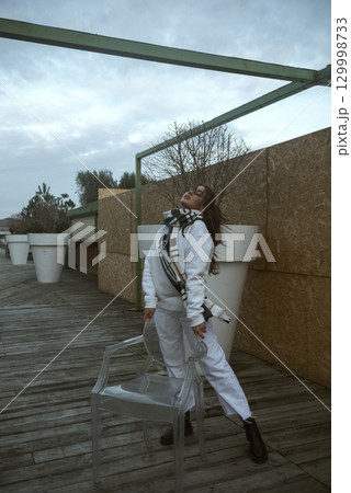 Beautiful young girl in a white tracksuit stands on the seashore in stormy weather 129998733