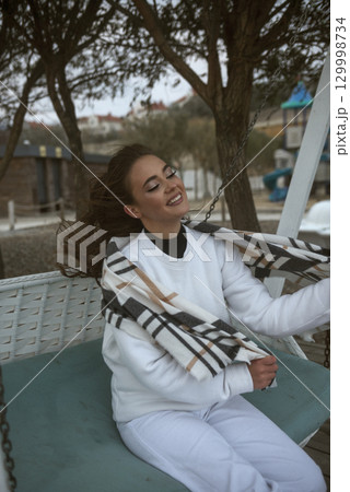 beautiful young girl with long dark hair swinging on a swing 129998734