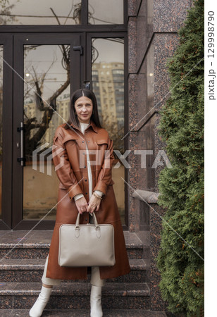 elegant woman over 40 exiting building with laptop bag elegant woman over 40 exiting building with laptop bag 129998790