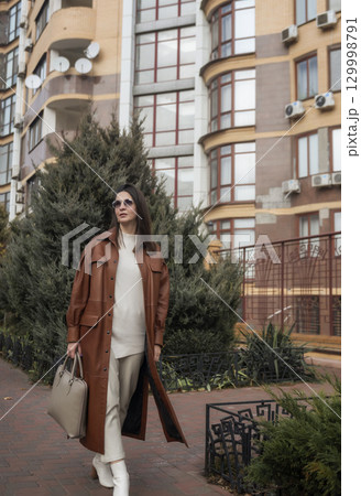 elegant woman over 40 exiting building with laptop bag elegant woman over 40 exiting building with laptop bag 129998791