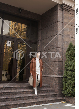 elegant woman over 40 exiting building with laptop bag elegant woman over 40 exiting building with laptop bag 129998794