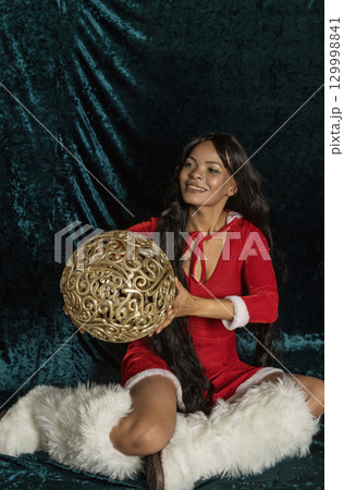 Dark-skinned beautiful girl in red New Year's dress with gold decor 129998841