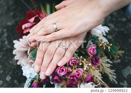 結婚指輪とブーケの上で重なる手 129998922