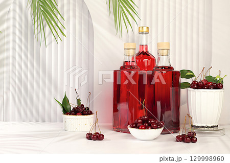 Homemade hard cherry cider in bottles on elegant background, still life with alcoholic drinks and fresh cherries, home winemaking concept, minimalist banner for bar, advertising banner for cafe 129998960