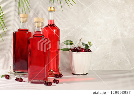 Homemade strong cherry cider in bottles and glasses on elegant background, still life with alcoholic drinks and fresh cherries, home winemaking concept, minimalist banner for bar, Homemade strong cherry cider in bottles and glasses on elegant background, still life with alcoholic drinks and fresh cherries, home winemaking concept, minimalist banner for bar, 129998987