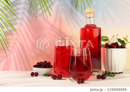 Homemade strong cherry cider in bottles and glasses on elegant background, still life with alcoholic drinks and fresh cherries, home winemaking concept, minimalist banner for bar Homemade strong cherry cider in bottles and glasses on elegant background, still life with alcoholic drinks and fresh cherries, home winemaking concept, minimalist banner for bar 129998989