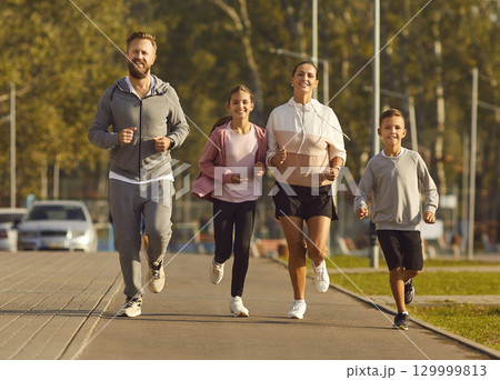 Active parents with their children do sports by running together in city park in morning. Active parents with their children do sports by running together in city park in morning. 129999813