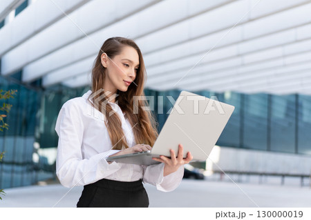 Confident businesswoman using laptop outside 130000019