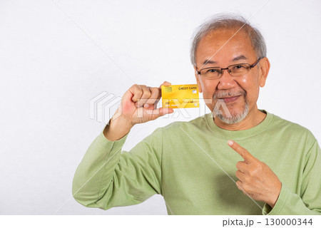 Portrait Asian smiling old man is holding credit card and pointing finger to card studio shot isolated on white background. happy grandfather elderly positive excited shopping online 130000344