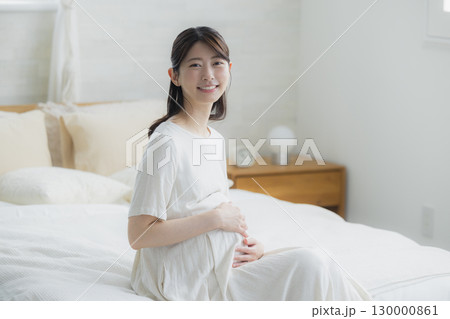 寝室でベッドに座る妊婦 寝室でベッドに座る妊婦 130000861