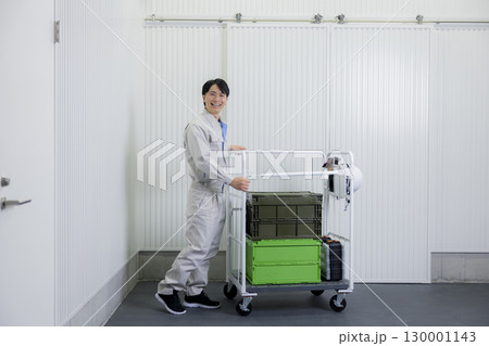 倉庫で台車を押す作業着の男性 130001143