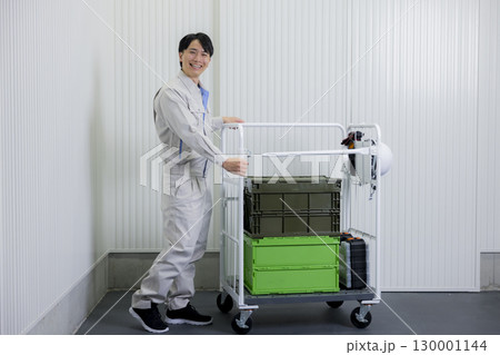 倉庫で台車を押す作業着の男性 130001144