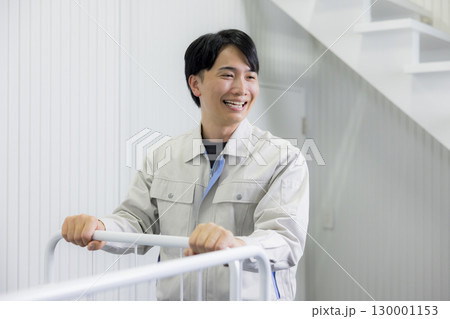 倉庫で台車を押す作業着の男性 130001153