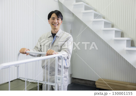 倉庫で台車を押す作業着の男性 130001155