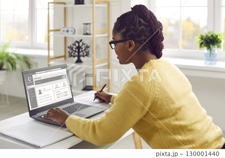 Young African American business woman using online banking website on her laptop Young African American business woman using online banking website on her laptop 130001440