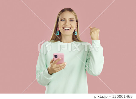 Portrait of happy girl with smartphone celebrating victory raising one fist 130001469