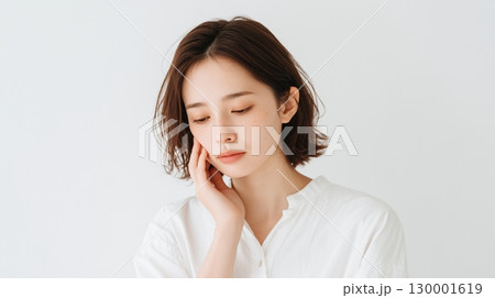 頬に手を当てて悩む表情の女性アップ 130001619
