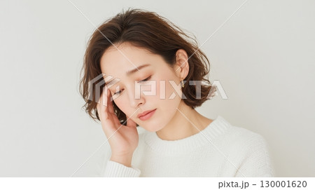 こめかみに手を当てて悩む表情の女性アップ 130001620