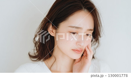 頬に手を当てて不安そうに見つめる女性　痛みや心配を表現 130001778