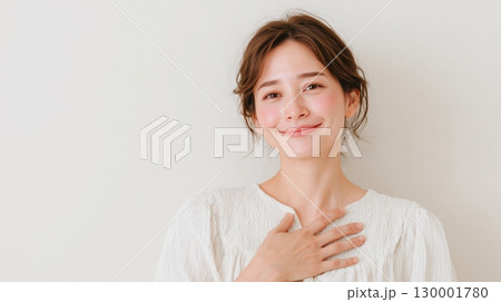 胸に手を当てて微笑む女性　安心感や感謝を表すポーズ 130001780