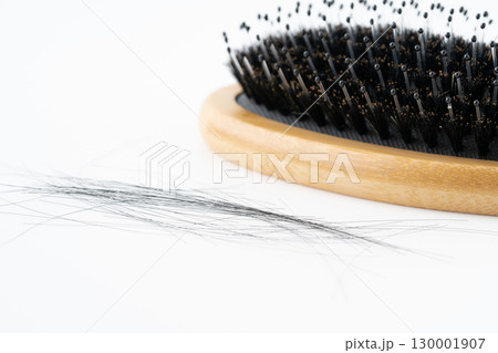 白背景に豚毛のヘアブラシと抜けた髪の毛のクローズアップ 130001907