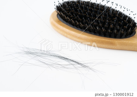 白背景に豚毛のヘアブラシと抜けた髪の毛のクローズアップ 130001912