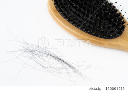 白背景に豚毛のヘアブラシと抜けた髪の毛のクローズアップ 130001913