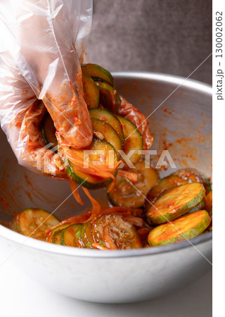 Korean cucumber salad (Oi muchim) mixing in bowl by hand, Korean side dish 130002062