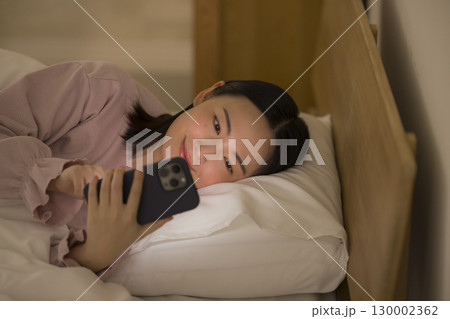 ベッドでスマホを見る女性 ベッドでスマホを見る女性 130002362
