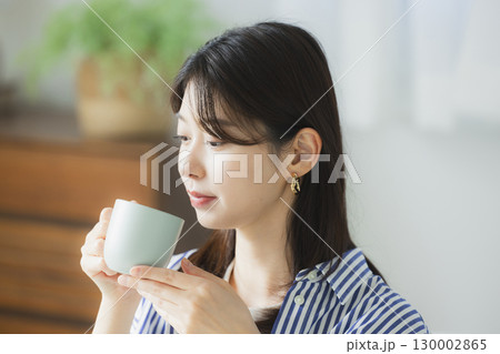 部屋でコーヒーを飲む若い女性 部屋でコーヒーを飲む若い女性 130002865