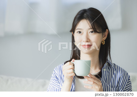 部屋でコーヒーを飲む若い女性 部屋でコーヒーを飲む若い女性 130002870