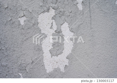 Peeling paint on gray concrete wall. Peeling, cracking, or blistering paint occurs when there is a loss of adhesion between the paint and the surface it's placed on. 130003117