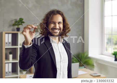 Portrait of a young happy smiling attractive man with house keys in his hands. 130003332